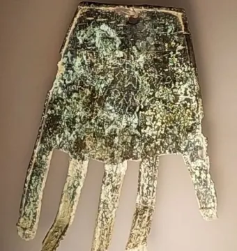 The Hand of Irulegi, an ancient hand-shaped artifact with engraved markings and a corroded green-brown surface.