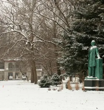 Lincoln the Lawyer statue standing in a snow-covered park beside a rectangular pillar.