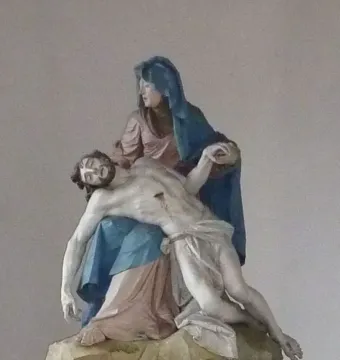 Nenningen Pietà sculpture showing Mary in blue and pink robes holding the lifeless body of Christ across her lap
