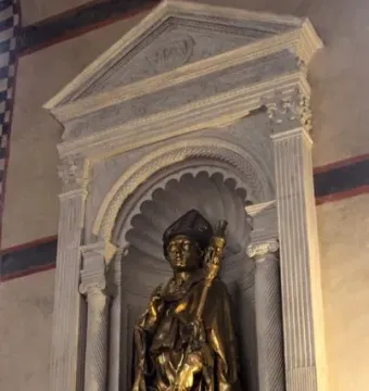Golden statue of Saint Louis of Toulouse in a carved stone niche with columns and a shell-shaped arch.