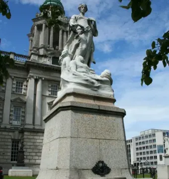 Titanic Memorial in Belfast, showing a robed female figure holding a laurel wreath above smaller figures on a granite pedestal.