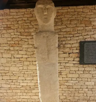 U Nativu stone bust against a dry-stone wall