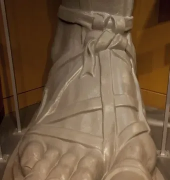 Close-up of the Vulcan statue’s right foot with detailed toes and sandal straps on a gray base.