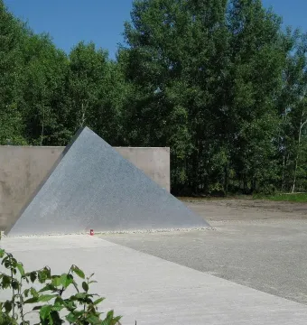 Hailfingen-Tailfingen Memorial with a textured triangular metal sculpture in front of a concrete wall.