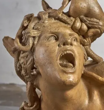 Screaming Medusa detail from Perseus and the Gorgon, with a contorted face, mouth agape, eyes looking upward, and snakes in the hair.