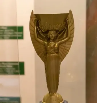 Jules Rimet Trophy with a winged female figure holding a laurel wreath above a spherical FIFA base.