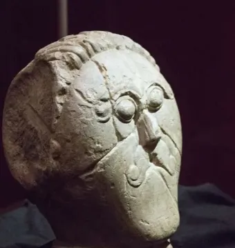 Mšecké Žehrovice Head with carved eyes, nose, and hairstyle on a dark stand.