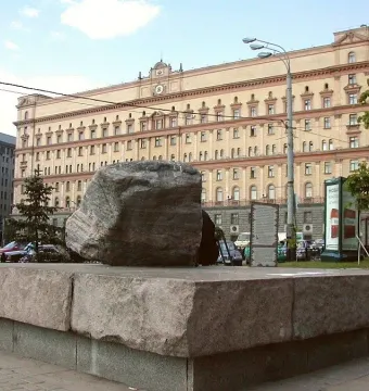 Solovetsky Stone monument, a large granite boulder on a stone base, with a beige building in the background.