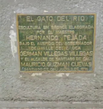 Weathered bronze plaque mounted on a textured light gray wall, with engraved Spanish text and names.