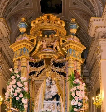 Madonna dell\'Udienza sculpture of the Madonna and Child displayed in a gilded shrine with flowers and crowns.
