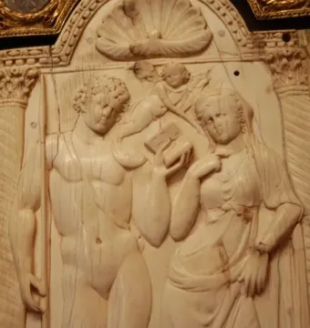 Queriniano Diptych ivory panel showing a man with a staff and a draped woman under an arch with a shell motif and cupid figures.