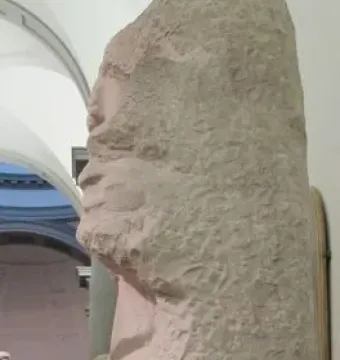Unfinished marble sculpture of Saint Matthew with a figure emerging from the stone.