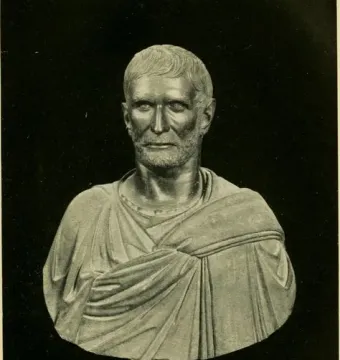 Capitoline Brutus bust with short wavy hair, a bearded stern face, and a draped garment on an ornate stand.