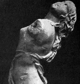 Partial stone sculpture of the Dancing Maenad shown in profile, with arched back and long hair swept backward.