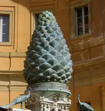 La Pigna bronze pine cone sculpture on an ornate carved stone base, flanked by two peacock statues.