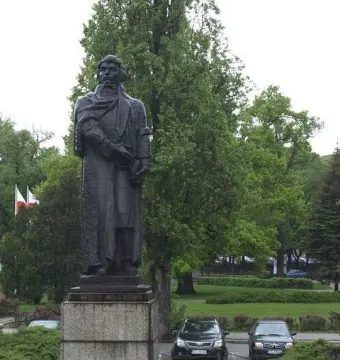 Mickiewicz Monument in Gorzów Wielkopolski, a dark statue of a man in a long coat holding a book on a stone pedestal.