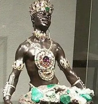 Moor with Emerald Plate statue holding a tray with green crystals, wearing a jeweled crown and ornate gold jewelry.