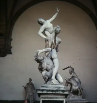 The Rape of the Sabine Women marble sculpture shows three intertwined figures in a dynamic pose inside an arched loggia.