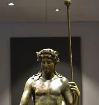 Tiber Dionysus bronze statue of a nude male figure holding a staff and wearing a wreath.