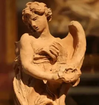 Terracotta sculpture of Angel with the Crown of Thorns, shown with a draped body, downward gaze, and a thorny crown held near the chest.