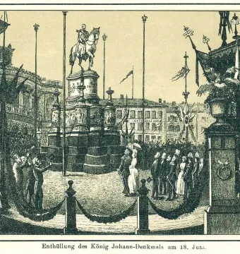 The King Johann Memorial stands on a tiered pedestal in a decorated public square during its unveiling, with a crowd gathered around it.