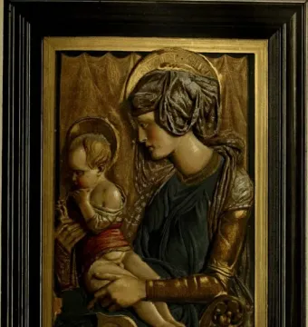 Painted terracotta relief of Madonna and Child with halos, the woman in blue and gold holding a child in red against a gilt background.