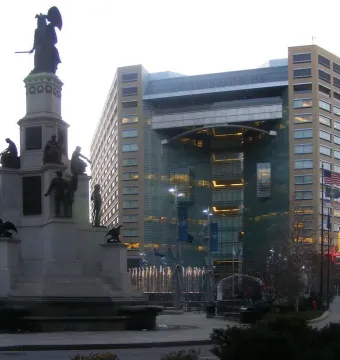 Michigan Soldiers\' and Sailors\' Monument in a city plaza with a modern glass-and-stone building behind it.