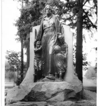 Pioneer Mother Memorial statue of a woman with three youths holding her garments, set on a rocky base with a fountain below.