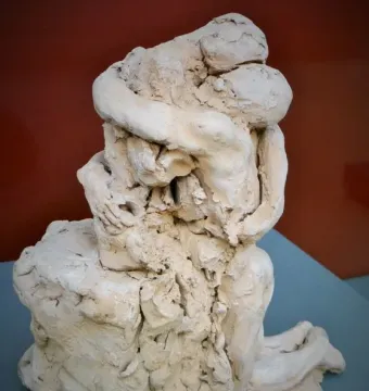 Sakuntala sculpture showing two intertwined figures in a rough terracotta embrace.