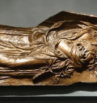 Bronze figure from the Shaw Memorial with flowing drapery, leaves at the chest, and a rectangular panel behind the head.
