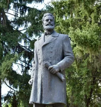 Bronze monument to Hristo Botev showing a bearded man in a long coat holding a rolled document.