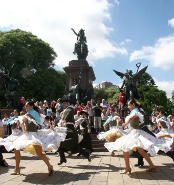 José de San Martín equestrian statue above dancers in traditional dress performing in a park