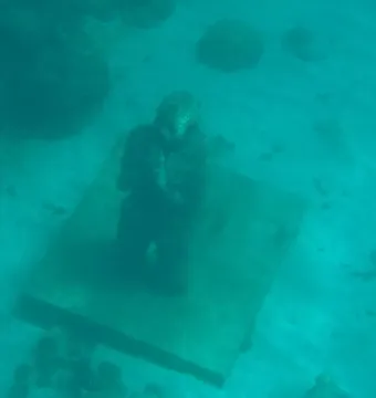 Molinere Underwater Sculpture Park figure sculpture kneeling on a base underwater.