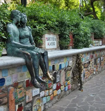 The Muretto of Alassio, a stone wall covered with colorful signed ceramic tiles and a bronze couple sculpture.