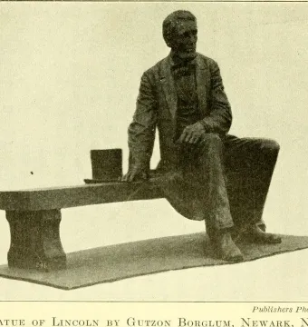 Bronze Seated Lincoln sculpture of Abraham Lincoln seated on a long bench with a top hat beside him.