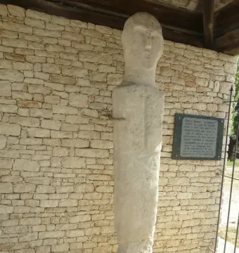 U Nativu stone menhir standing against a light stone wall
