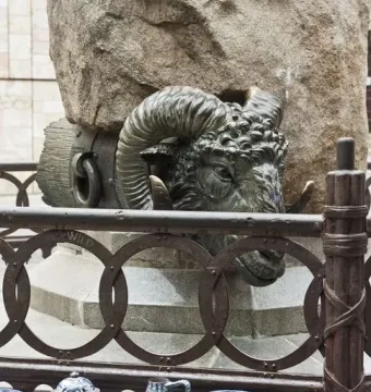 Bronze ram head at the Monument to Viriato, with blue and white ceramic vessels in front of a stone pillar.