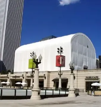 Cloud Gate covered by a large white tent in a city plaza.