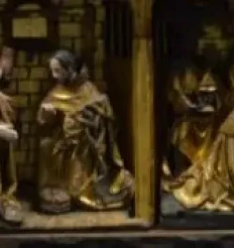 Lower register of the Fisenne Altarpiece showing gilded carved scenes with several figures gathered around an infant or basin.