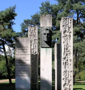 Julius Fučík Memorial with five stone pillars, including a central pillar with a metal bust and carved inscriptions.