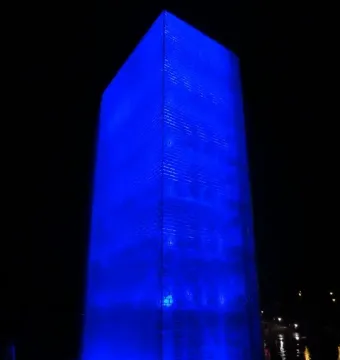 A tall, rectangular blue-lit structure of Crown Fountain glows at night.