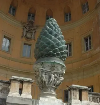 La Pigna, a large green pine cone sculpture on an ornate stone pedestal in front of a curved building.