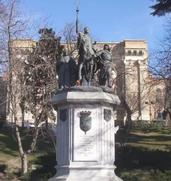 Monument to Isabella of Castile showing a bronze equestrian statue on an ornate marble pedestal in a shallow pool.