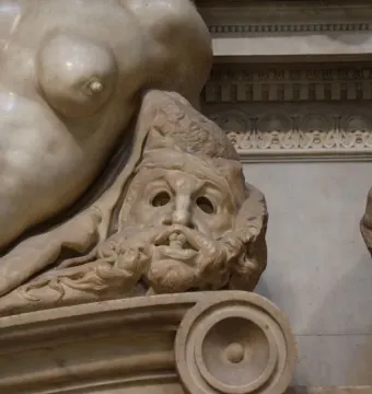 Detail of Michelangelo\'s Night showing a reclining female figure and a grimacing bearded face below her.