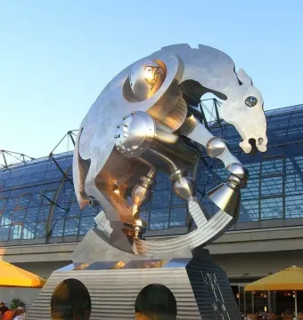 Rolling Horse sculpture in front of a modern glass building under a clear blue sky.