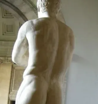 Apoxyomenos, a marble nude male statue seen from behind in a museum setting.