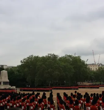 Guards Memorial with a parade of guards in red uniforms and bearskin hats standing in the courtyard.