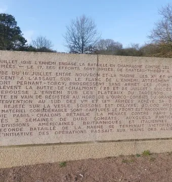 The Ghosts memorial stone with a long French inscription in a grassy outdoor setting.