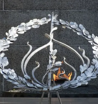 Unknown Soldier Monument detail with a wreath of leaves around an eternal flame set against a dark stone wall.
