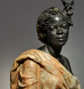 Bust of Woman from the French Colonies with dark textured hair, an ornate hair ornament, and a draped garment over her shoulders.